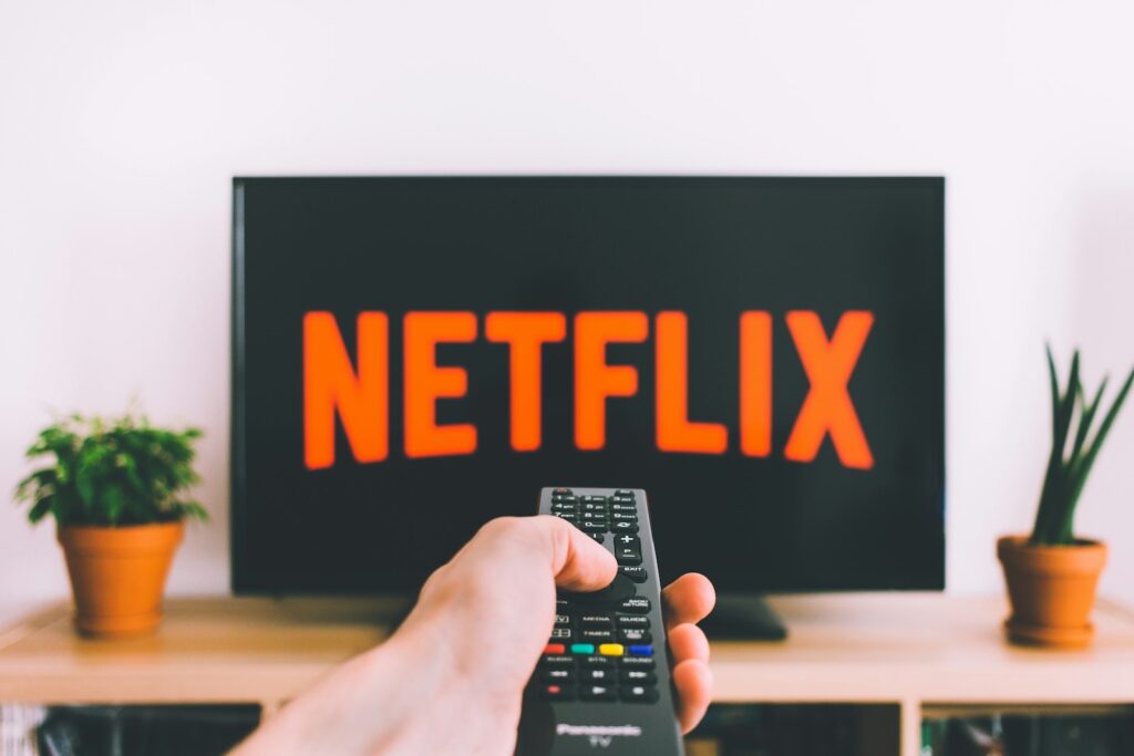 Hand mit Fernbedienung vor einem Fernseher mit Netflix-Logo